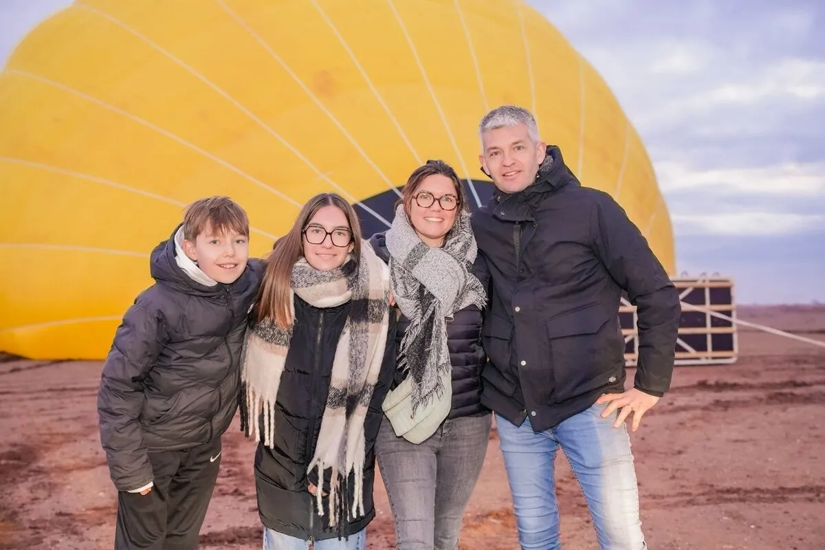 Family posing for photo in front of yellow hot air balloon in Marrakech